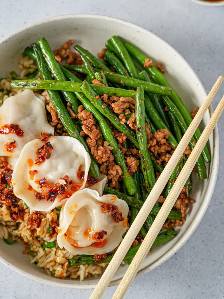 A colorful plate of beans paired with fried rice and dumplings, showcasing vibrant ingredients