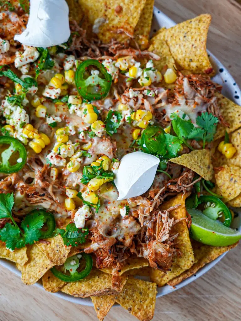 Slow cooker chicken nachos topped with melted cheese, served on a plate.