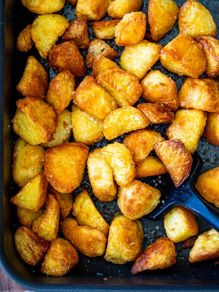 Crispy golden roast potatoes arranged in a baking tray